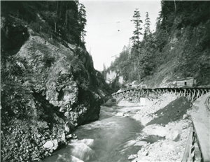 Wooden trestle along right side of steep gorge of rushing river