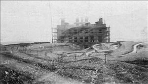 Maryhill museum under construction with scaffolding extending beyond the building amongst winding valley hills and rows of agriculture in the foreground