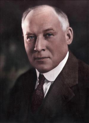 Head and shoulders portrait of a balding man in a suit coat and tie. 