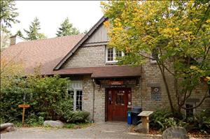 A wood and brick lodge building with a red door. Trees surround the building. 