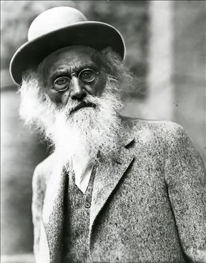 Elderly white man in rimless eyeglasses and large hat, with a bushy white beard