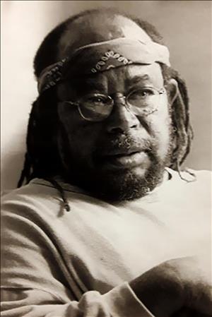 A Black man with dreads glasses and a bandana around his head