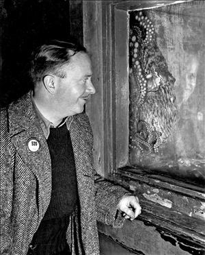 Haglund smiling in a tweed coat while looking at an octopus in the aquarium