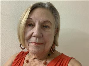 A head and shoulders portrait of a woman against a beige background. 