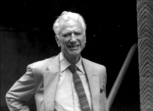 An older white man in a light colored blazer and tie. 