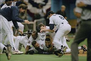 Numerous members of Seattle Mariners baseball team pile atop Ken Griffey after Griffey scored the winning run in the team's first playoff victory.