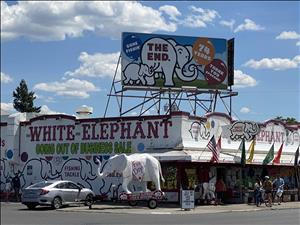 A one story building with an elephant statue in front and a billboard on the roof that says 'The End'
