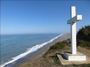 A white cross on a bluff overlooking the ocean