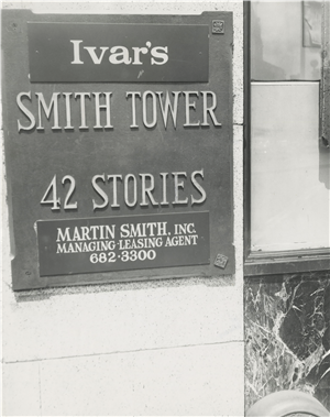 A plaque on a stone building says Ivar's Smith Tower forty two stories martin smith inc managing leasing agent. 
