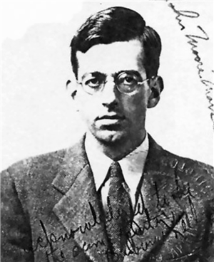 Head and shoulders portrait of a white man in suit and tie wearing rimless eyeglasses. 