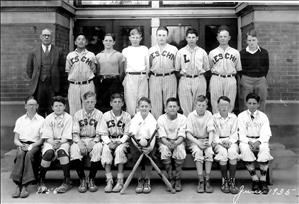 Two rows of children posing for a photo. Front row is seated. Back row is standing. They are all wearing baseball uniforms that says Leschi, pronounced Lesh Eye. 
