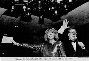 A woman in a sequined dress holds out a piece of paper in front of a man holding a microphone and holding up one hand. Beneath them text says Sharon and Dick Friel have brought their hand in glove style to more than 500 fundraising auctions. 