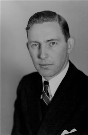 Head and shoulders portrait of a man in a suit and tie. 