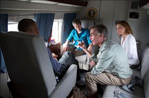 Four people sit in a circle on an airplane listening to one of the group speak.