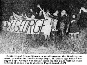 In a newspaper clipping, a group of people stand in tall grass waving their arms in the air while holding a banner that says Hey George.