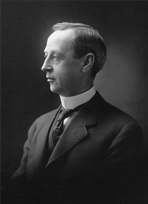 A head and shoulders profile portrait of a white man in a suit and tie and starched white collar. The image is black and white. 