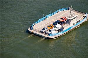 Small car ferry, with six or so vehicles occupying about half its open deck, viewed from above