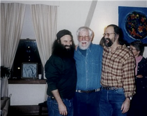 Three white men with beards stand arm in arm laughing. 