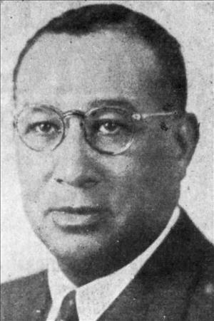Frazier posing in glasses and suit