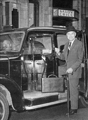 Thal in bowler hat, suit and cane stepping into a vehicle with the Savoy Grill in the background