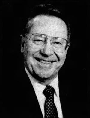 An older McNaughton smiling in suit and tie