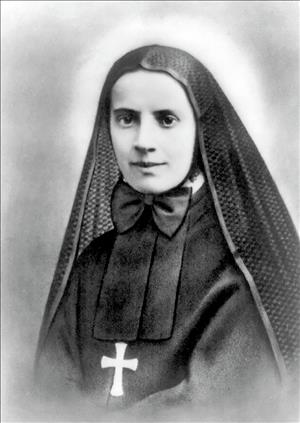 Cabrini posing in a nun's habit, wearing a gold cross necklace and a large black bow