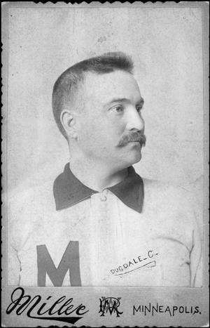 A younger Dugdale posing with a mustache and a white jersey with dark collar and the letter M on the chest