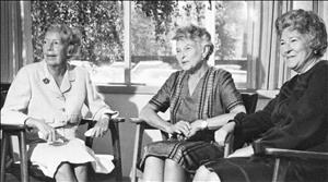 Buxbaum and two other women sitting in midcentury wooden chairs in front of a sunny window