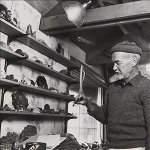Callahan in knit cap and sweater looking at rocks and ceramic figures on wooden shelving