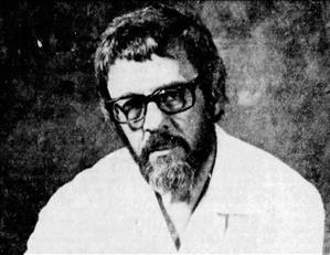 Olsen posing in thick rim glasses, shaggy hair and a beard