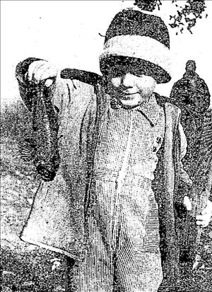 Child in a striped knit cap, coat and jumpsuit holding up two small fish