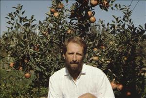 A white man with a beard in front of an apple tree