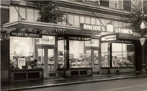 A one-story storefront with a sign that says Rhodes Ten Cent Stores. 