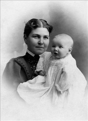 Woman smiling with a child wearing a large white gown