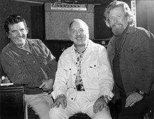 Three white men seated and smiling for the camera