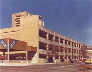 A three story concrete parking garage under a blue sky. 