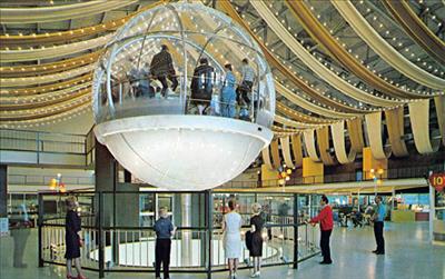 Several people observe the Bubbleator, a clear, plexiglass orb on a hydraulic lift that carried millions of visitors between floors at the Washington State Coliseum during the 1962 Seattle World’s Fair.