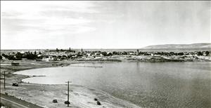 Black and white image of a lake with a town in the distant background