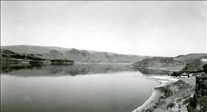 Black and white image of a lake with a few houses on the shore
