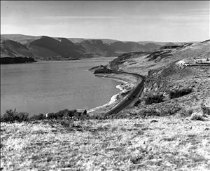 Black and white image looking down on soap lake. Cars on the highway next to lake. 
