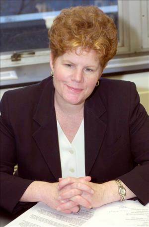 Crunican sitting with hands folded wearing black blazer